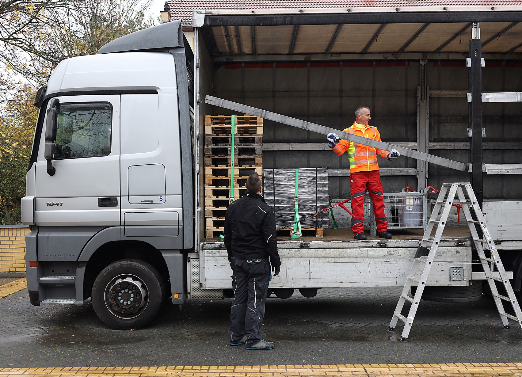 Zwei Männer bei der Arbeit vor einem offenen Lkw