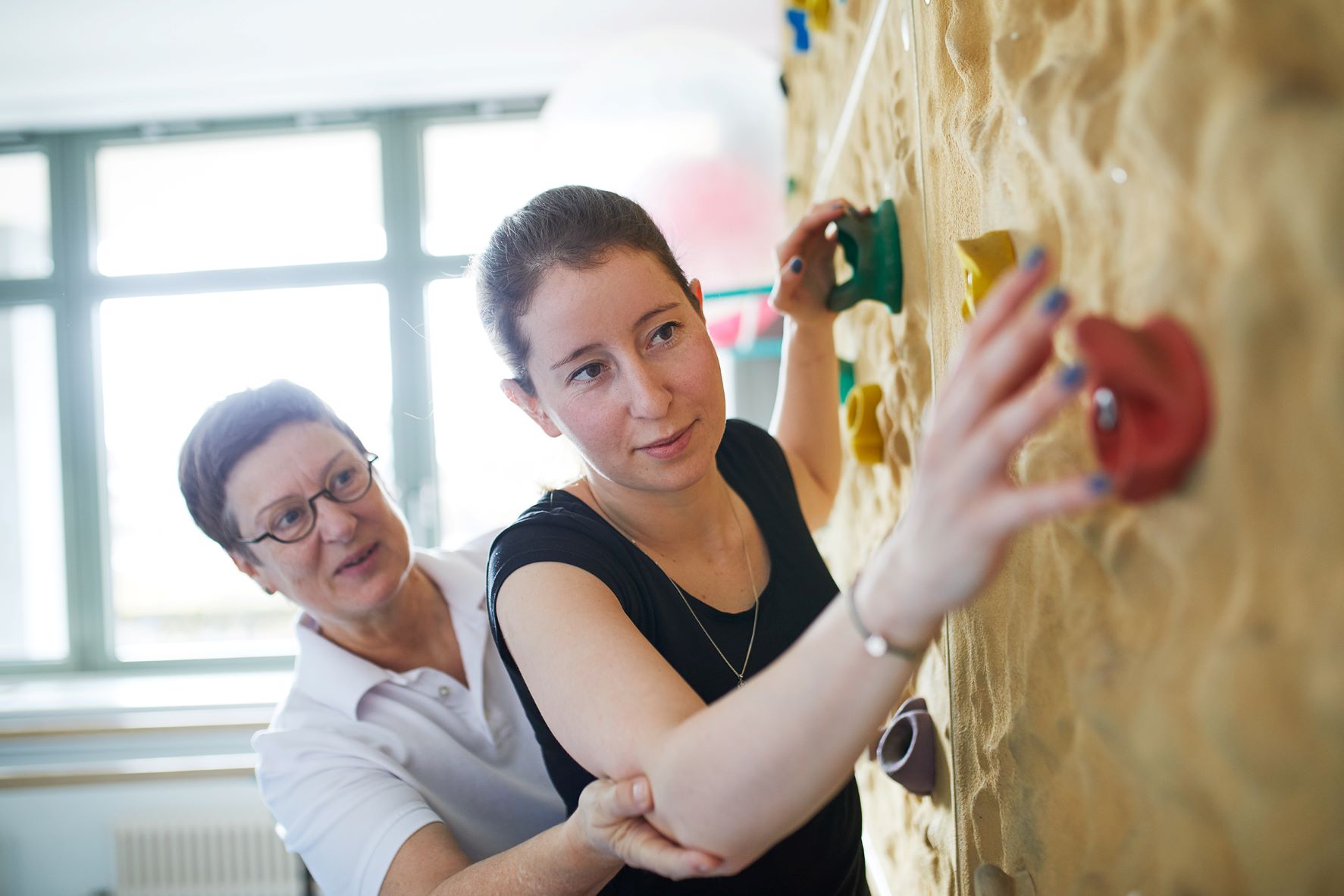 Frau mit Therapeutin an der Boulder Wand