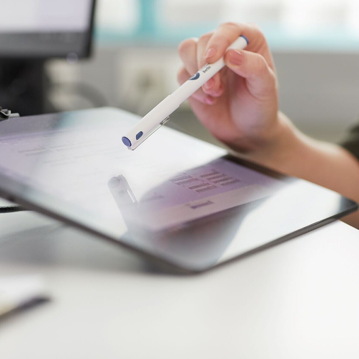 Hand mit Kugelschreiber auf einem Tablet