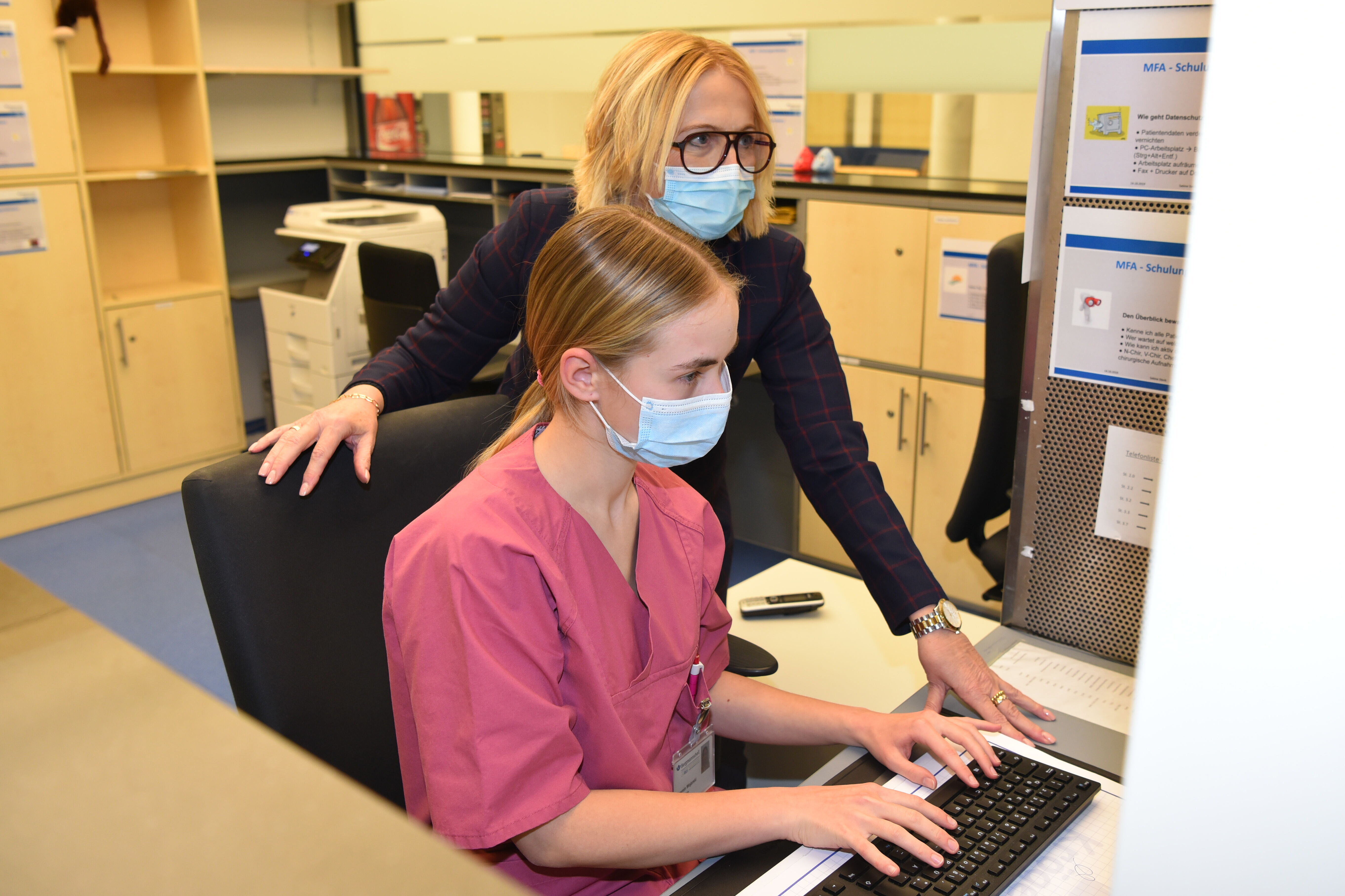 Auszubildende sitzt am Computer, ihre Ausbilderin schaut ihr über die Schulter