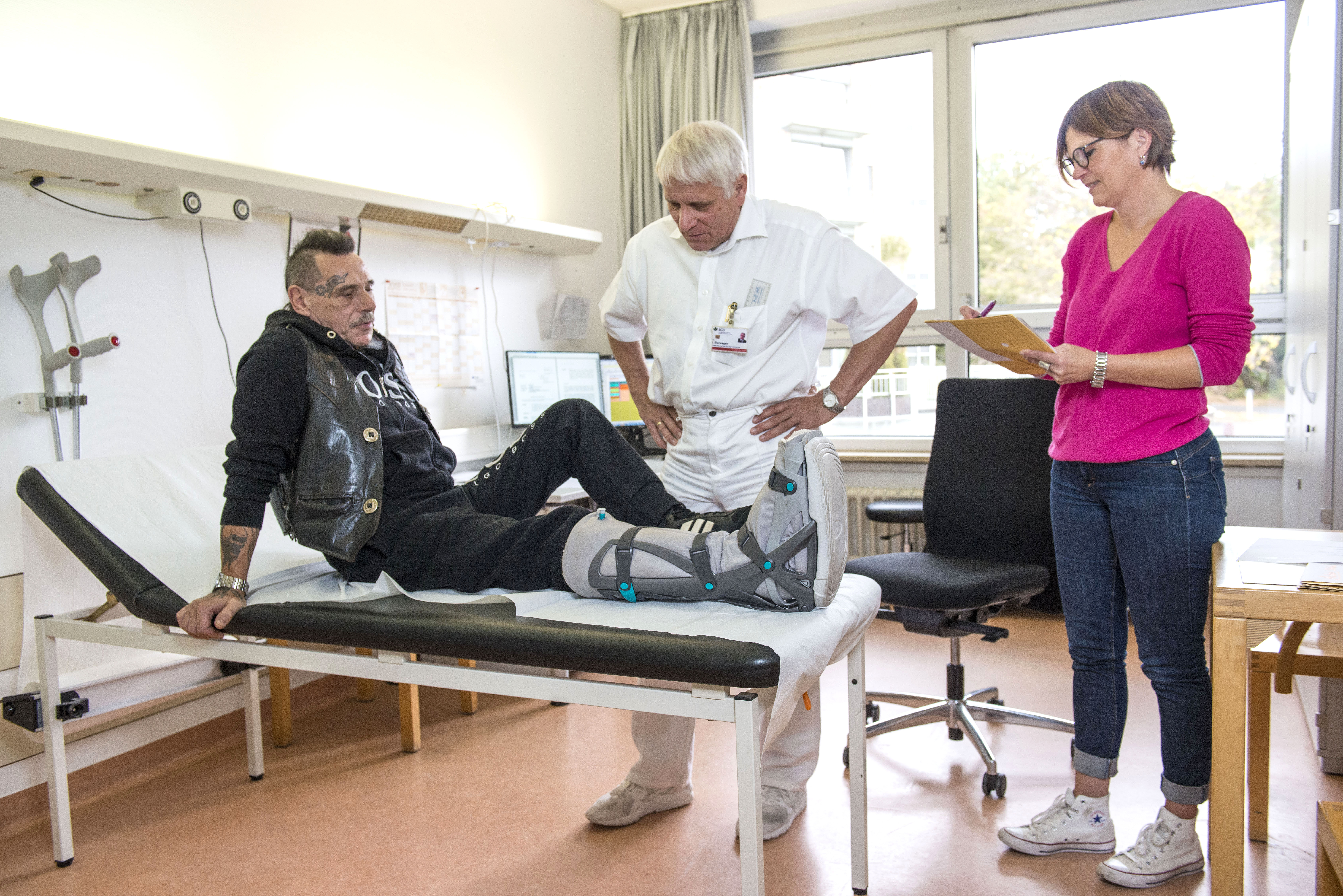 Arzt mit Rehaberaterin und Patient in der Sprechstunde